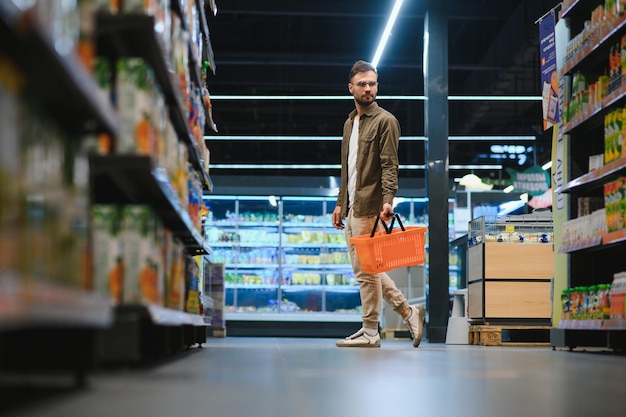 Giovane bello che sceglie cibo nel supermercato