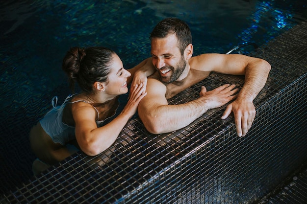 Giovane bello che si rilassa in una piscina coperta