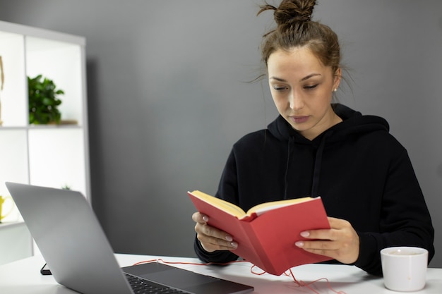 Giovane bello libro di lettura della donna in Ministero degli Interni durante l'autoisolamento