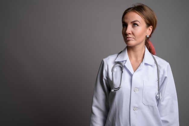 Giovane bello medico della donna contro la parete grigia