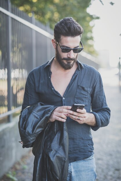 giovane bello modello uomo barbuto attraente utilizzando smartphone