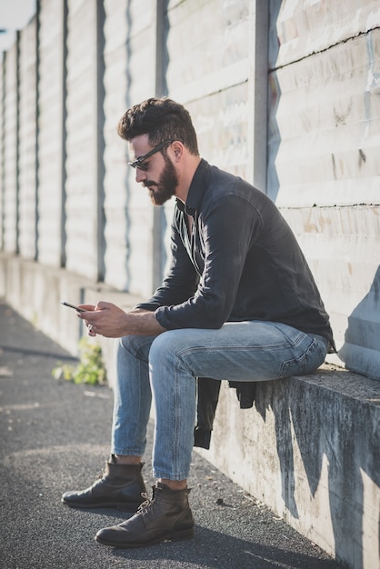 giovane bello modello uomo barbuto attraente utilizzando smartphone