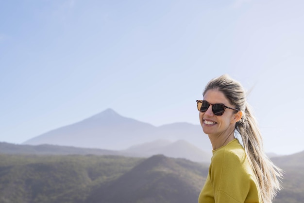 Giovane bionda caucasica con un grande sorriso al punto di vista del Monte Teide in una giornata limpida