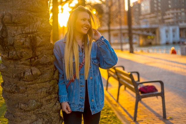 Giovane bionda pensierosa in un albero con una giacca da cowgirl su un tramonto