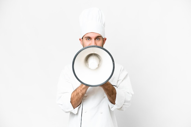 Giovane biondo Chef su sfondo bianco isolato gridando attraverso un megafono