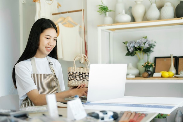 Giovane blogger di moda asiatica della donna di affari che mostra i prodotti del cesto intrecciato con la faccia sorridente