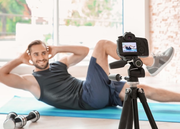 Giovane blogger sportivo che registra video sulla fotocamera a casa