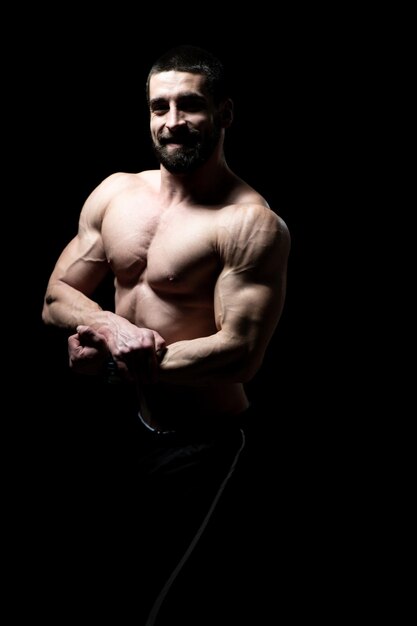 Giovane bodybuilder che flette i muscoli isolare sullo spazio nero della copia di Blackground