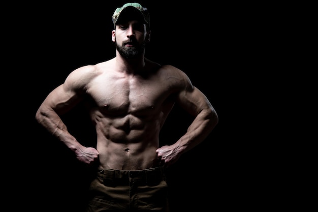 Giovane bodybuilder che flette i muscoli isolare sullo spazio nero della copia di Blackground