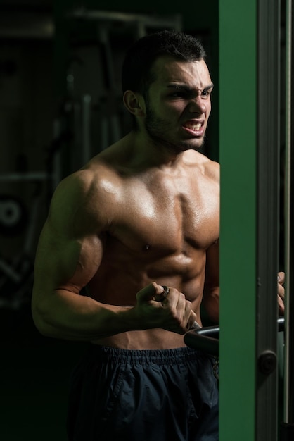 Giovane bodybuilder esercizio in palestra sta eseguendo due braccia bicipiti push up