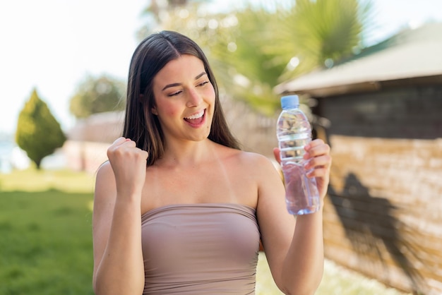 Giovane brasiliana con una bottiglia d'acqua all'aperto che celebra una vittoria