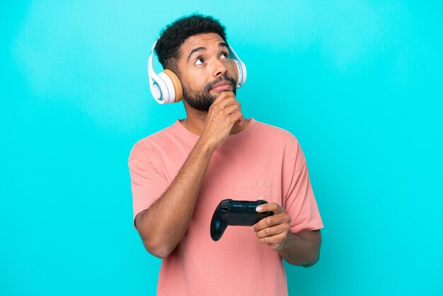 Giovane brasiliano che gioca con un controller per videogiochi isolato su sfondo blu e alza lo sguardo