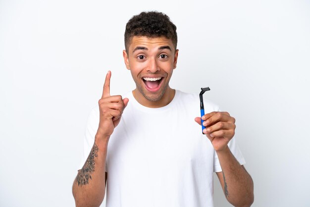 Giovane brasiliano che si rade la barba isolato su sfondo bianco che punta su una grande idea