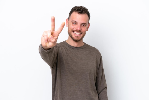 Giovane brasiliano isolato su sfondo bianco sorridente e mostrando il segno di vittoria