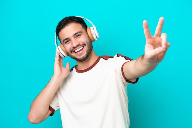 Giovane brasiliano isolato su sfondo blu ascoltando musica e cantando