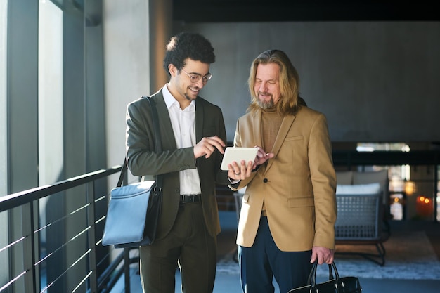 Giovane broker sorridente che scorre i dati online durante la presentazione