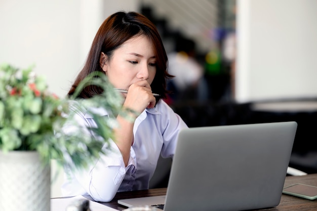 Giovane buisnesswoman serio che lavora con il computer portatile in ufficio.