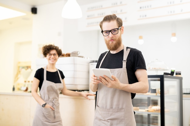 Giovane cameriere contento in caffetteria