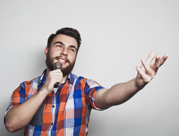 Giovane cantante uomo con microfono su sfondo grigio