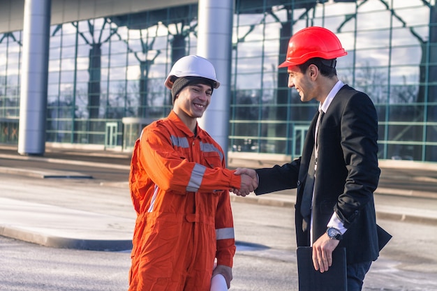 Giovane capo e lavoratore in conversazione si stringono la mano.