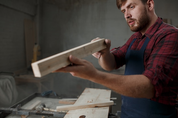 Giovane carpentiere con un grembiule nella sua officina