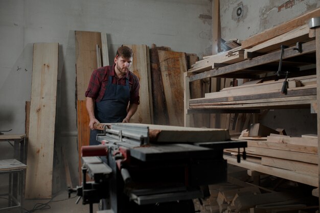 Giovane carpentiere con un grembiule nella sua officina