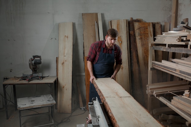 Giovane carpentiere con un grembiule nella sua officina