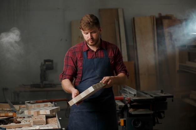 Giovane carpentiere con un grembiule nella sua officina