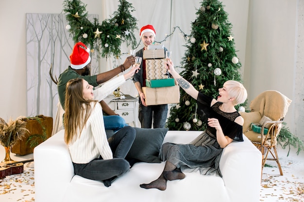 Giovane caucasico che presenta i regali di Natale agli amici sul divano alla festa di Capodanno