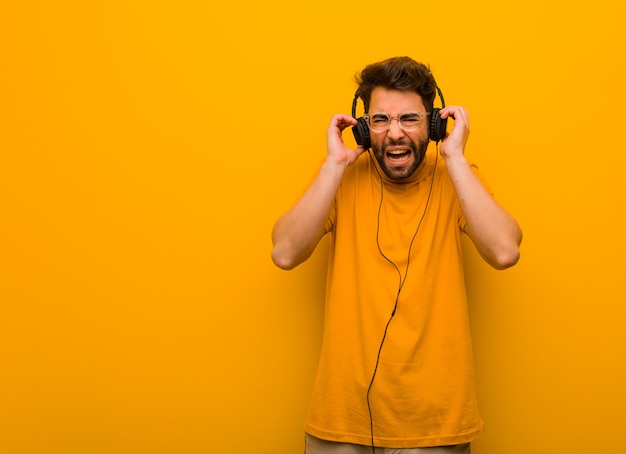 Giovane che ascolta la musica che copre le orecchie con le mani