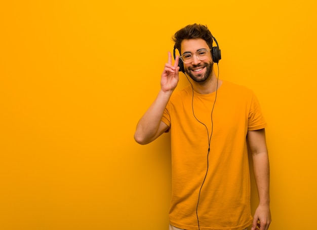 Giovane che ascolta la musica divertente e felice facendo un gesto di vittoria