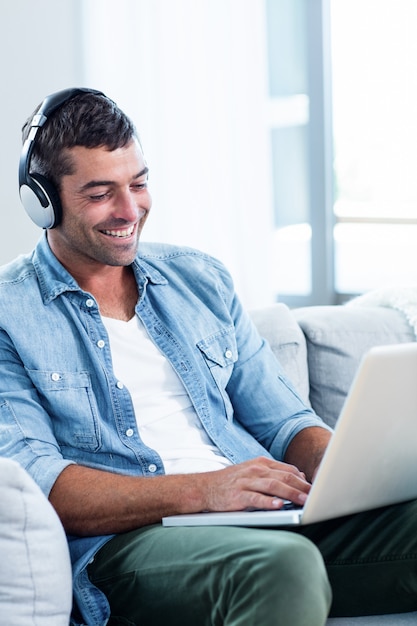 Giovane che ascolta la musica mentre per mezzo del computer portatile