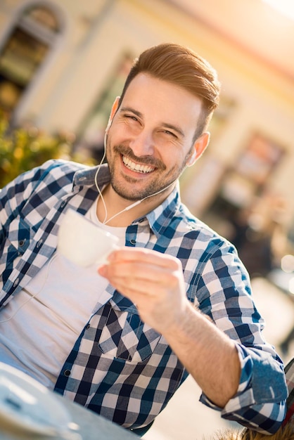 Giovane che ascolta la musica su uno smart phone. Sta ascoltando musica sullo smartphone in città.