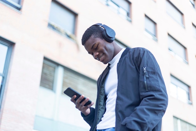 Giovane che ascolta musica mentre usa il telefono fuori dall'edificio