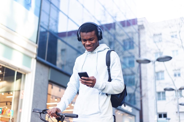 Giovane che ascolta musica mentre usa il telefono fuori dall'edificio