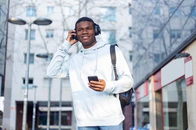 Giovane che ascolta musica mentre usa il telefono fuori dall'edificio