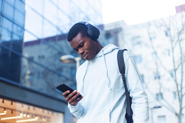 Giovane che ascolta musica mentre usa il telefono fuori dall'edificio