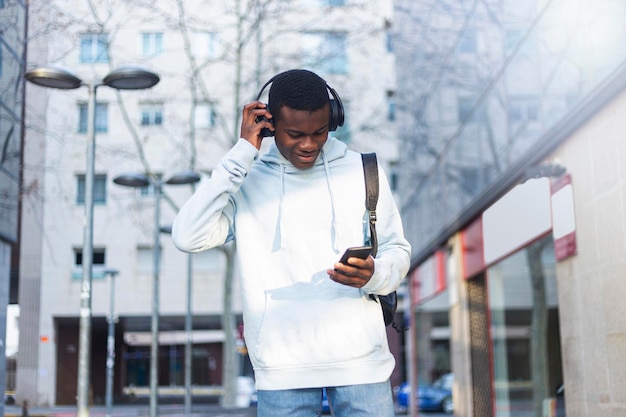 Giovane che ascolta musica mentre usa il telefono fuori dall'edificio