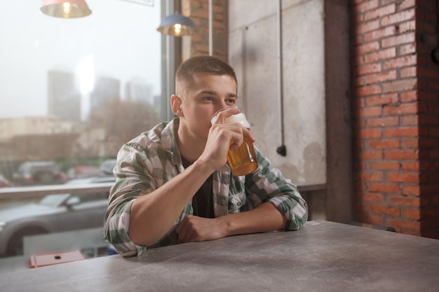 Giovane che beve birra al pub da solo