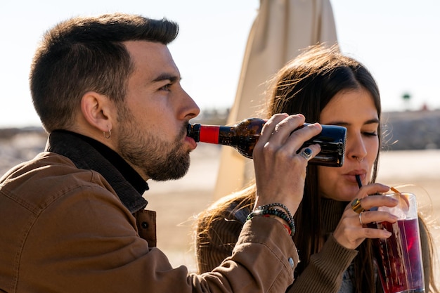 Giovane che beve birra e donna che gode del cocktail