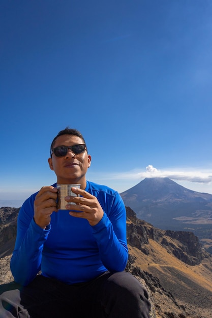 Giovane che beve caffè caldo in montagna