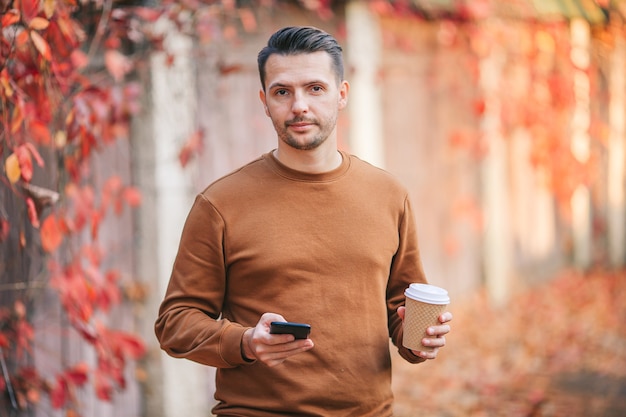 Giovane che beve caffè in autunno parco all'aperto