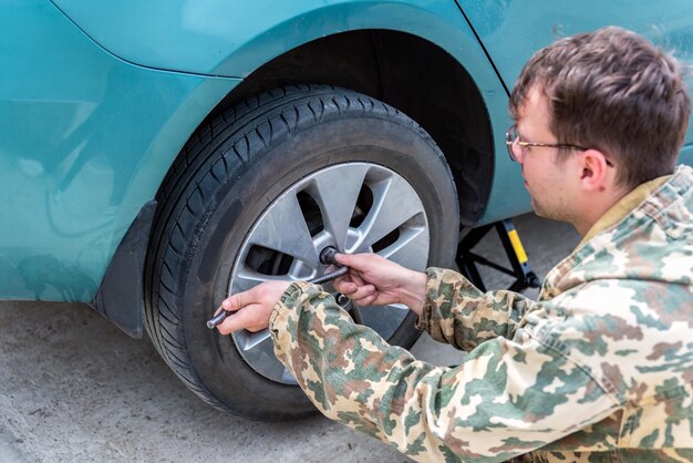 giovane che cambia una gomma d'auto per le gomme invernali