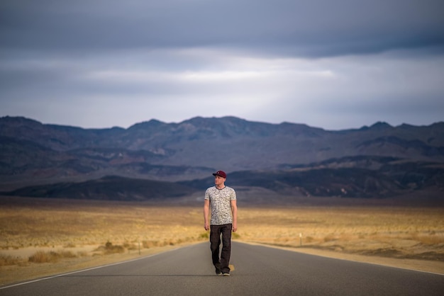 Giovane che cammina da solo attraverso una strada vuota nel deserto della Death Valley