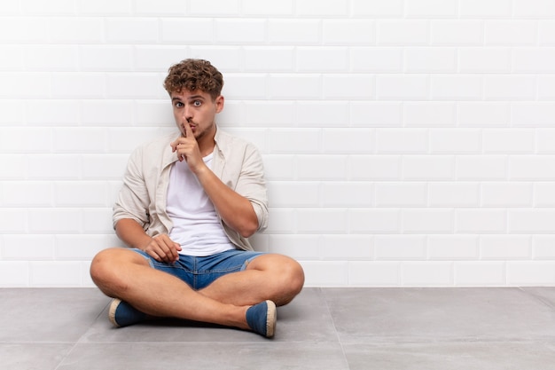 Giovane che chiede silenzio e silenzio, gesticolando con il dito davanti alla bocca isolata