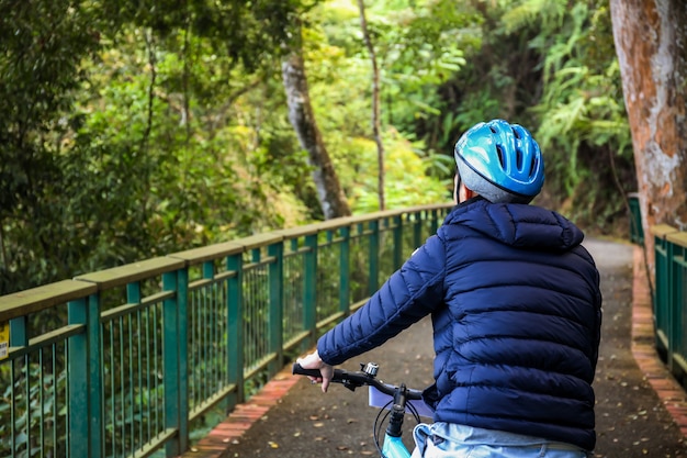 Giovane che cicla nella traccia della foresta in tempo freddo durante il fine settimana