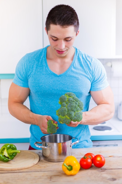 Giovane che cucina il formato del ritratto delle verdure del pasto sano nel mangiare della cucina