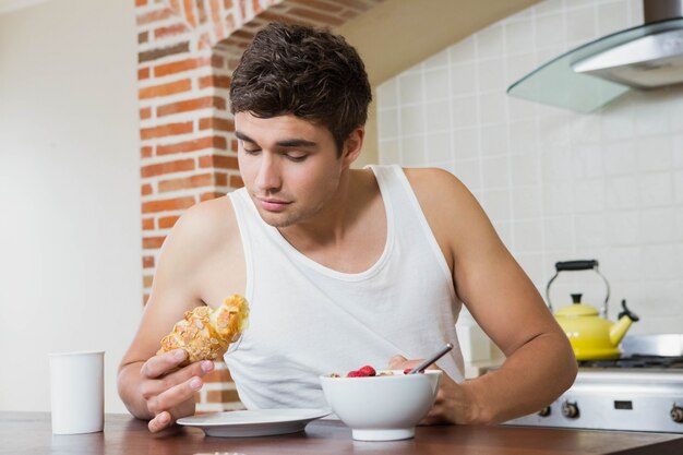 Giovane che esamina croissant mentre facendo colazione in cucina