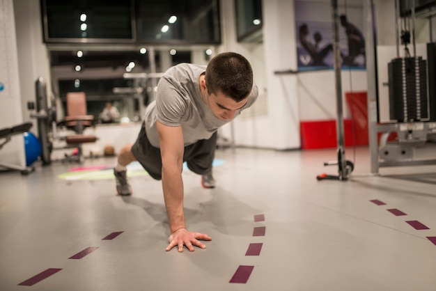 Giovane che fa i push-up da un lato in palestra