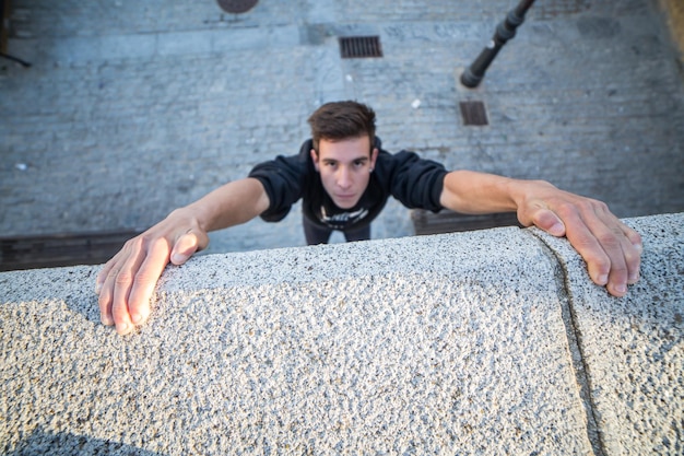 Giovane che fa parkour appeso a un muro